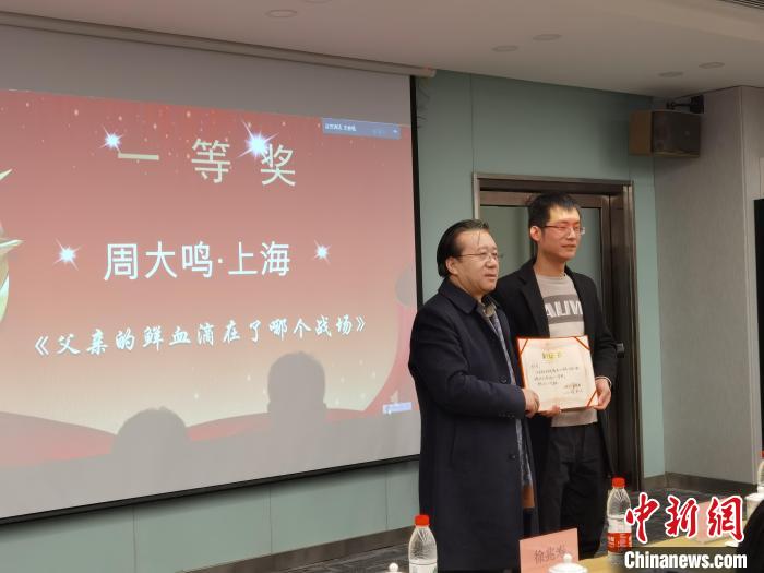 圖為作家、西北師范大學(xué)新聞與傳媒學(xué)院院長(zhǎng)徐兆壽頒發(fā)一等獎(jiǎng)證書(shū)，代領(lǐng)獎(jiǎng)?wù)呱吓_(tái)領(lǐng)獎(jiǎng)。　楊娜 攝