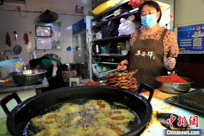 圖為平安驛·河湟民俗文化體驗地內的商戶炸干板魚。　薛蒂 攝